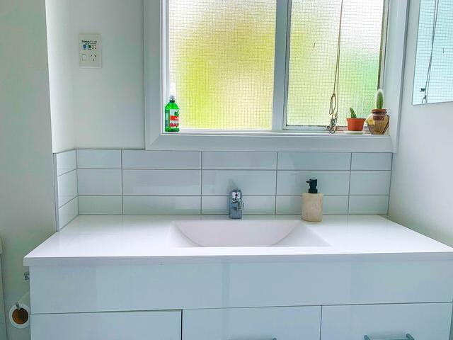 White bathroom vanity and tiled splashback under a bright window
