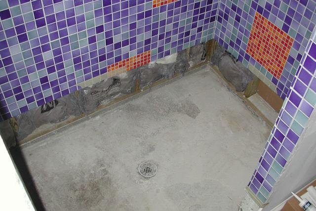 Shower floor with tiles and grout lines visible during repairs