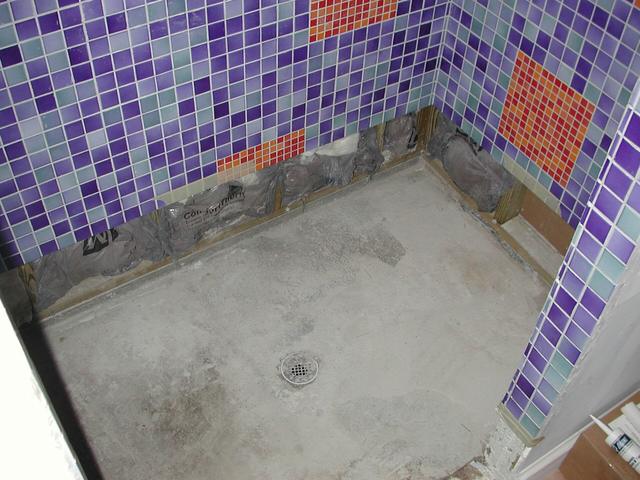 Shower floor with tiles and grout lines visible during repairs